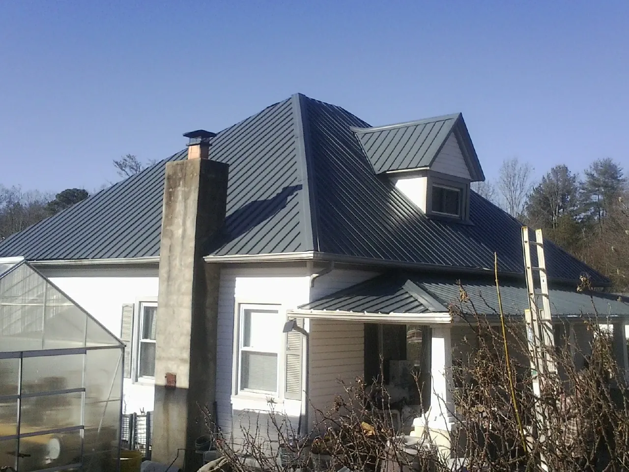 Dark blue standing seam metal roof on a white farmhouse with dormer — Slate & Tile Roof Repair by Roofing Brothers in Youngstown