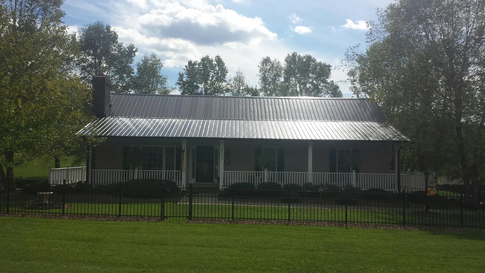 Gray metal roof on a brick ranch with a full width front porch — Gutter Guard Installation work by our crew in Youngstown