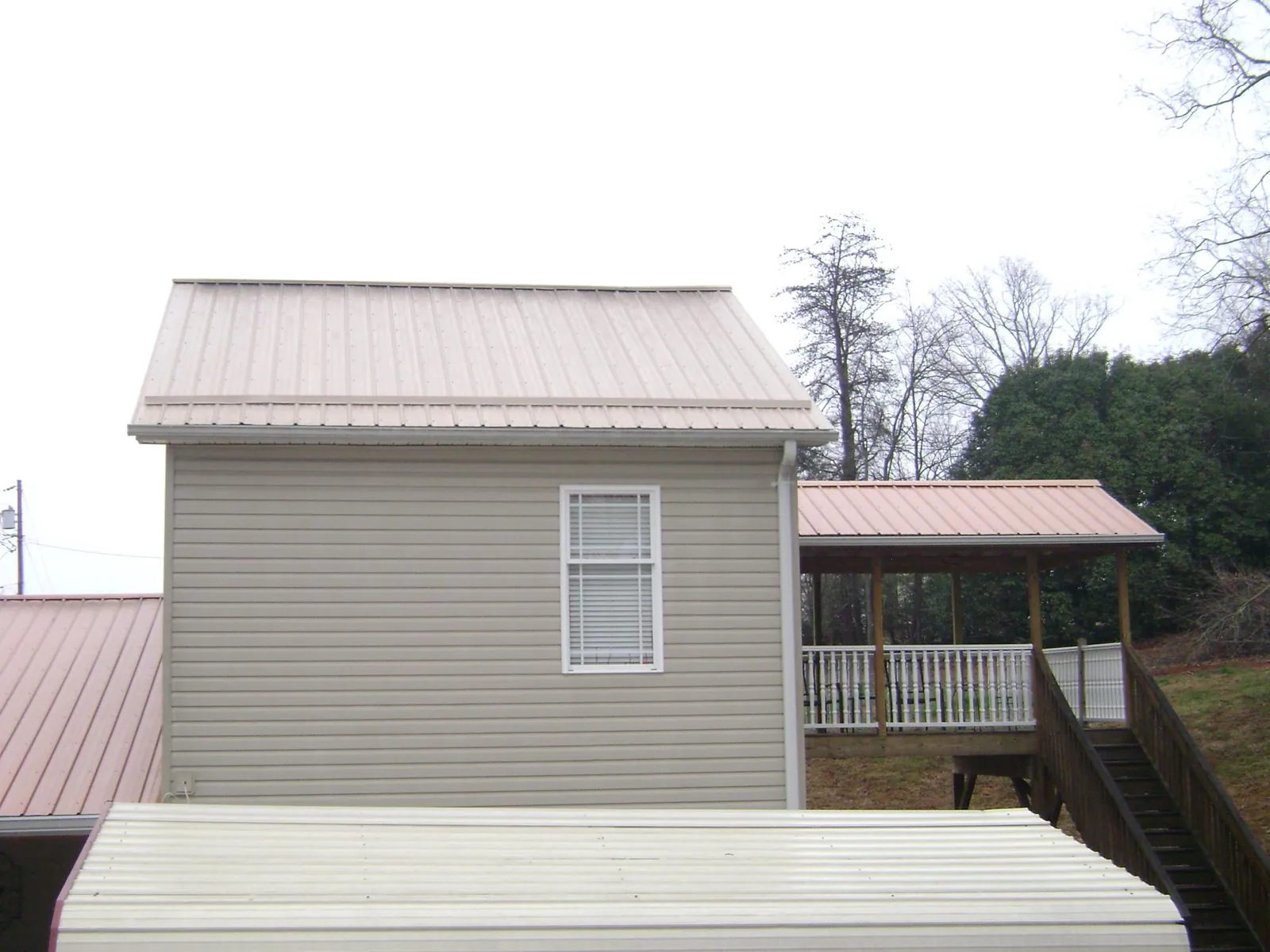 Tan metal roofs on a two story addition and attached porch, from a Roof Replacement job in Youngstown