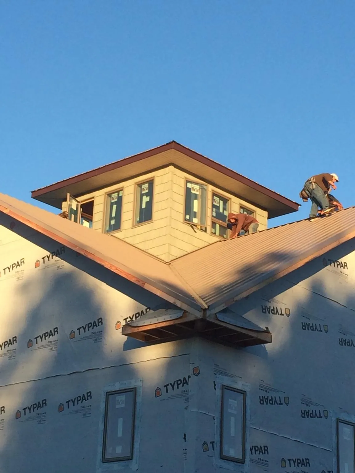 Roofers working around a rooftop cupola on a new metal roof at sunset — Roof Waterproofing in Youngstown by Roofing Brothers